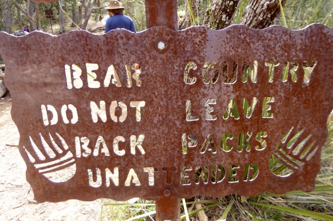 metal sign. Text says, "Bear Country Do Not Leave Back Packs Unattended"
