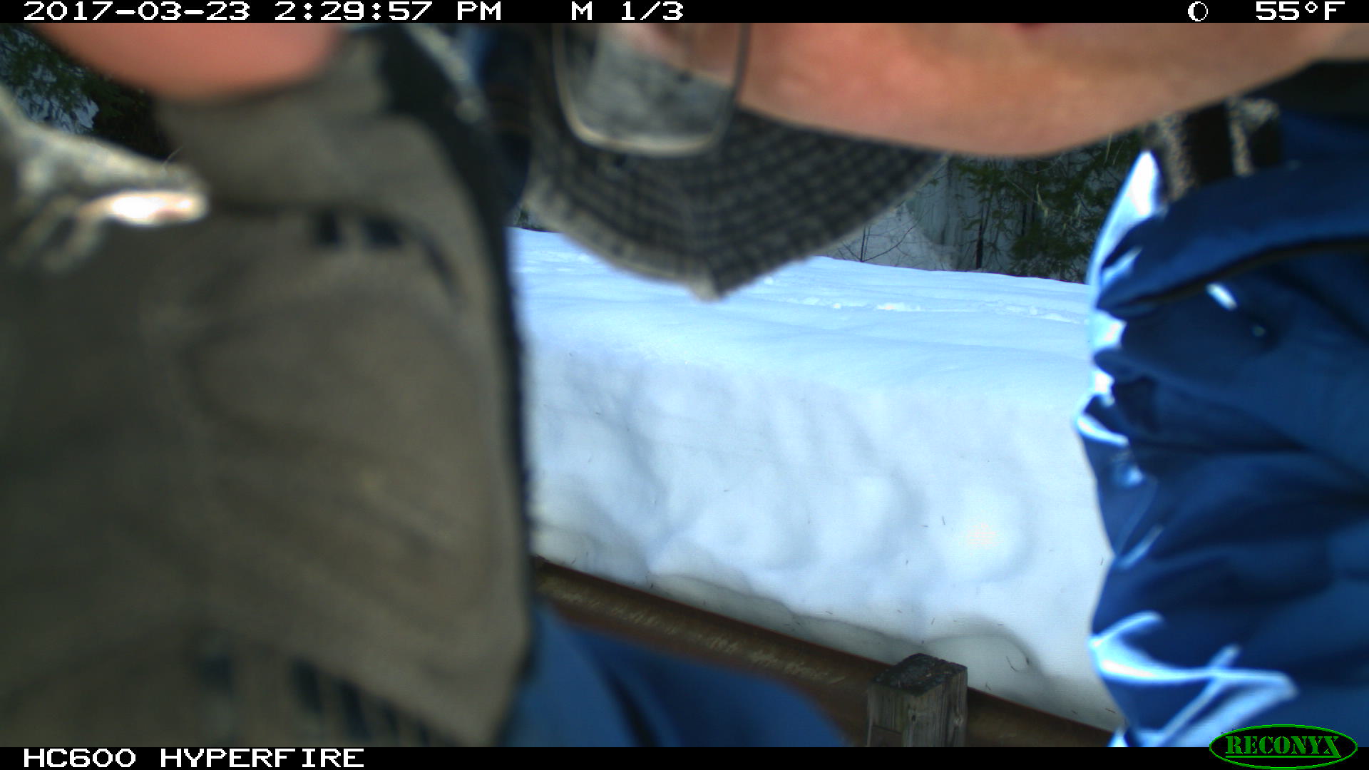 hand and part of person's face in front of camera, snow in background