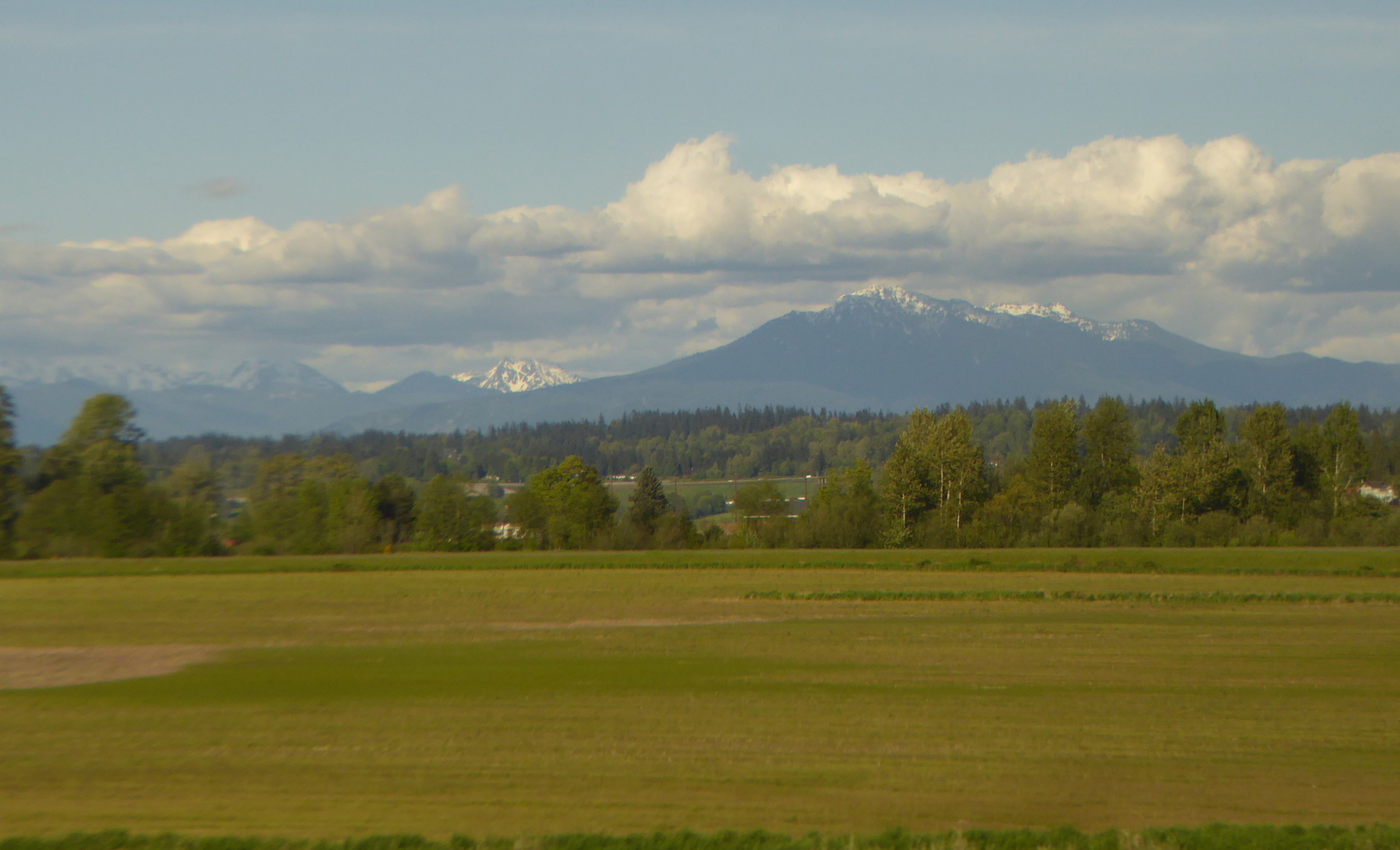 Farmland with view of tall snowcapped mountains in background
