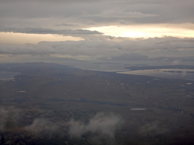 Aerial view of land, lake, and clouds.