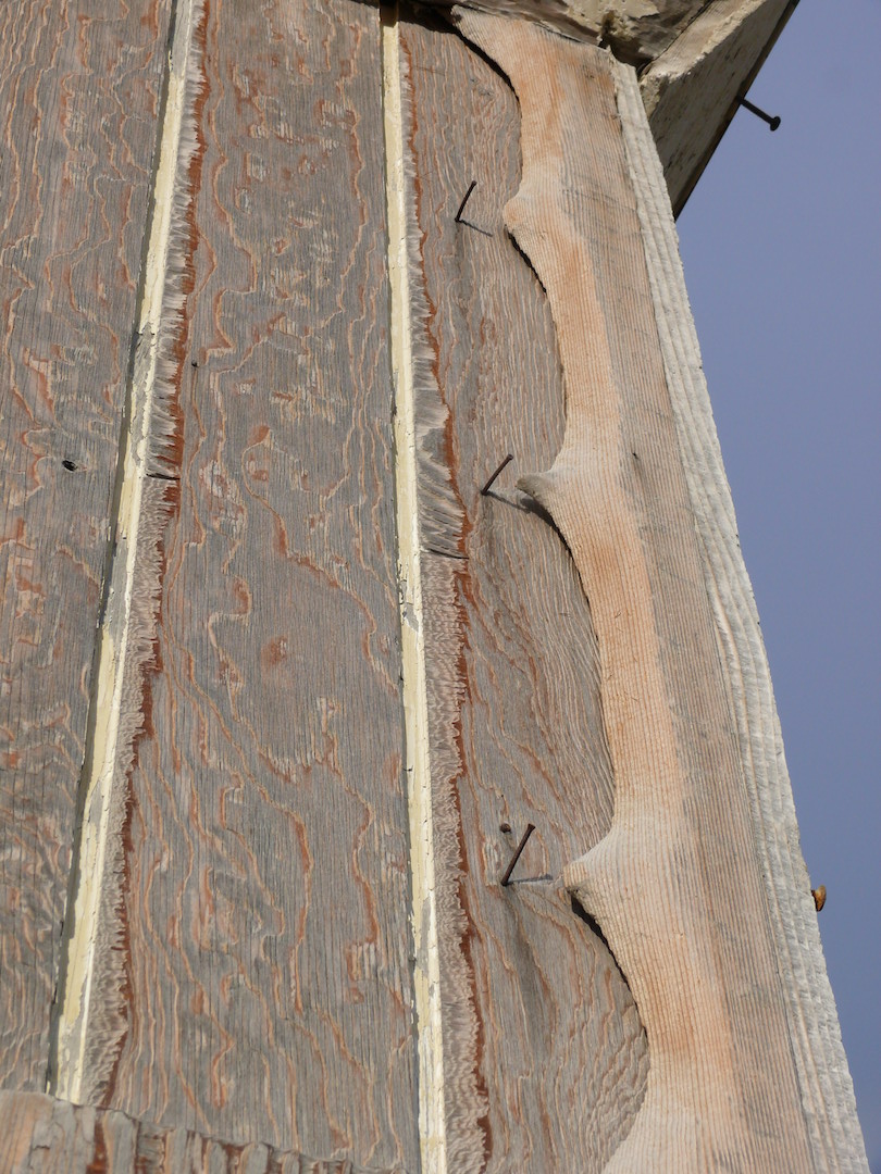 scalloped edge of wood and nails on building