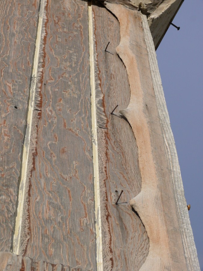 scalloped edge of wood and nails on building