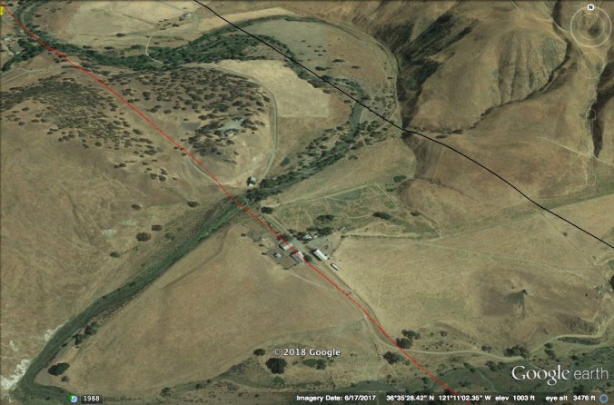 Google Earth image of creek valley with buildings at center.
