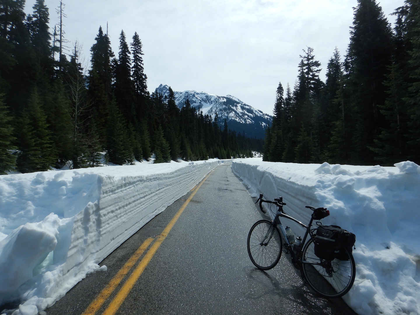bicycle leaning against snow bank with one lane of plowed highway
