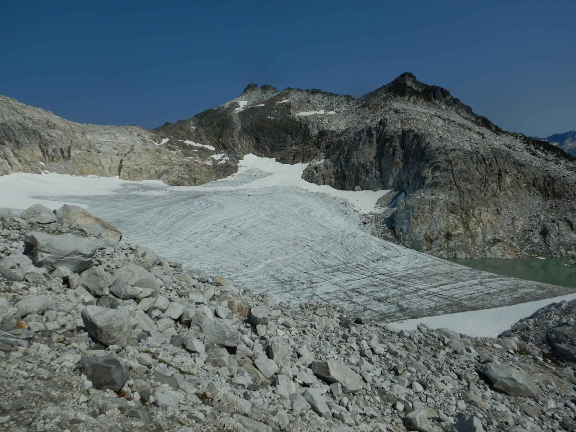 small, mostly snow free glacier tucked in a basin below a mountain peak