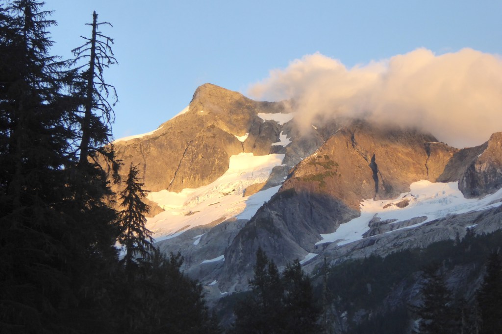 late day sun on craggy mountain peak and clouds