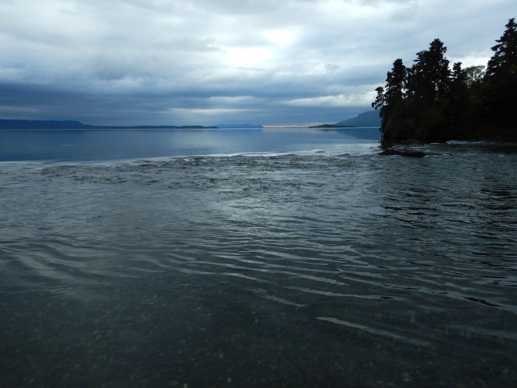 view of lake and shallow river on overcast day. Water flow is toward photographer and to right.