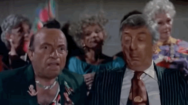 GIF. Pee Wee Herman yells at man with mohawk, "You're not going to vote for another bear are you?!?" Man looks at Pee Wee with alarm.